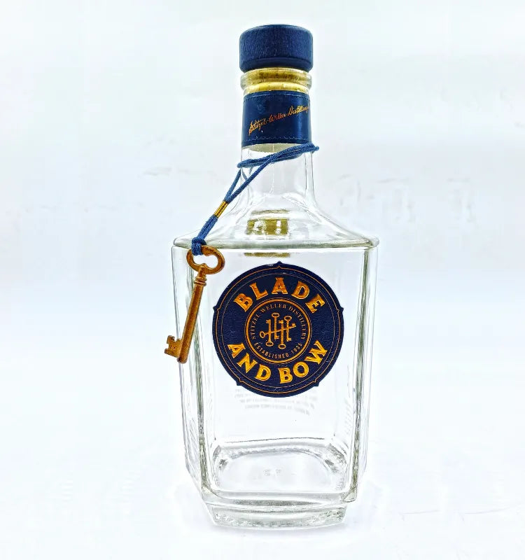 Upcycled Blade and Bow glass bottle canister filled with mixed nuts and dry fruits. Octagonal shaped glass with branded label, clear lid, and small key accent. Unique serving dish for home decor and aesthetic presentation."