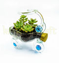 Artistic tricycle-shaped planter made from recycled glass bottles, featuring smooth clear glass with subtle blue and gold detailing — a one-of-a-kind eco-conscious décor accent handmade in India.