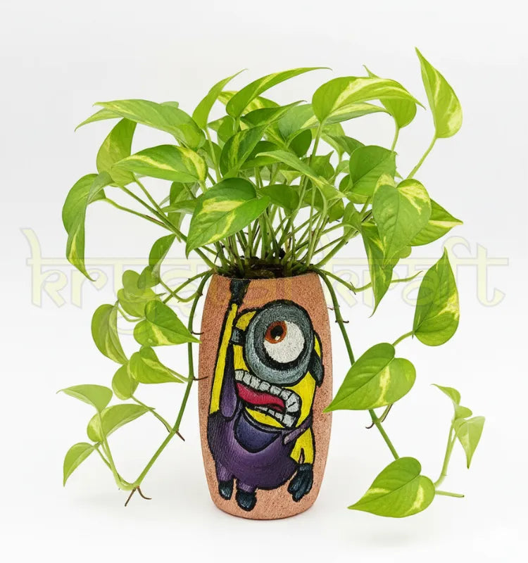 Hand-painted Hanging Minion design on a recycled Amul mini glass bottle with purple and yellow acrylics on a pink base — an eco-friendly mini vase or pen stand by Krystal Kraft.