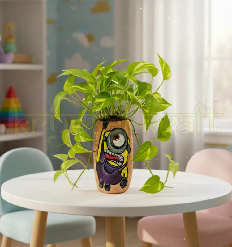 Hand-painted Hanging Minion design on a recycled Amul mini glass bottle with purple and yellow acrylics on a pink base — an eco-friendly mini vase or pen stand by Krystal Kraft.