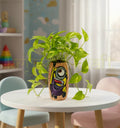 Hand-painted Hanging Minion design on a recycled Amul mini glass bottle with purple and yellow acrylics on a pink base — an eco-friendly mini vase or pen stand by Krystal Kraft.