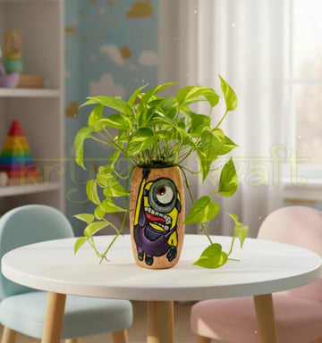 Hand-painted Hanging Minion design on a recycled Amul mini glass bottle with purple and yellow acrylics on a pink base — an eco-friendly mini vase or pen stand by Krystal Kraft.