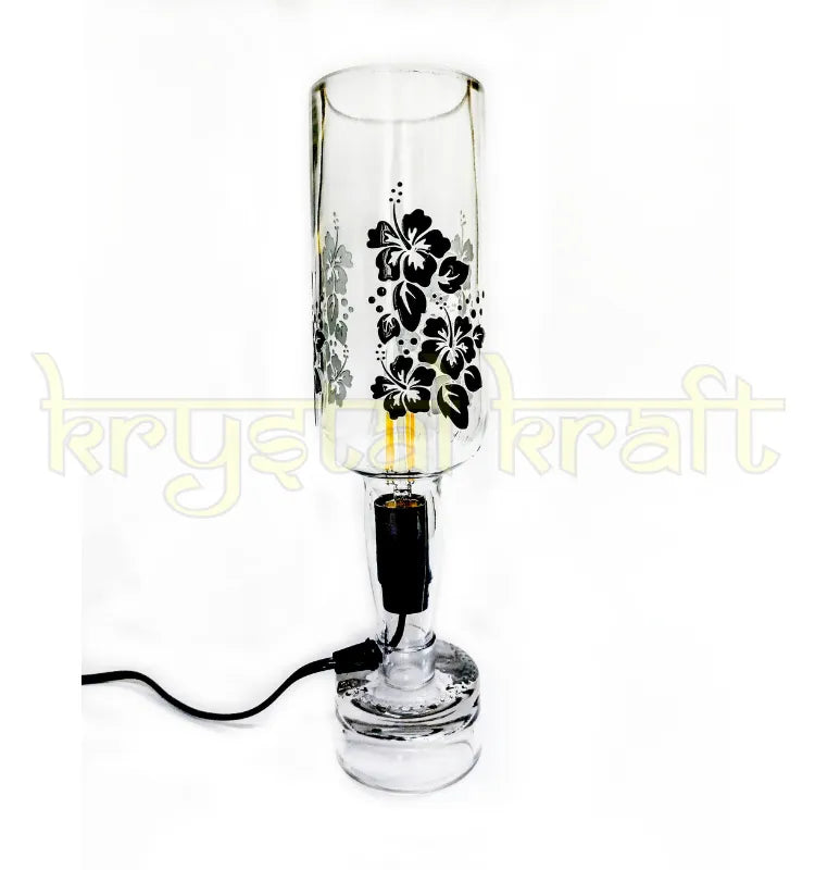 Indri printed bottle table lamp switched on beside a bed, casting warm light over a nightstand with books