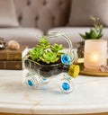 Upcycled glass tricycle planter handcrafted by artist Raees Ahmed Merchant — made from repurposed glass bottles with blue and gold accents, ideal as a sustainable home or office décor piece or indoor planter.