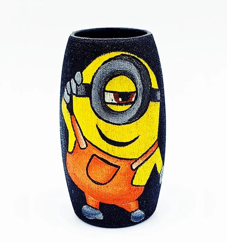 Recycled Amul mini bottle hand-painted with a Cool Minion on a black base using orange and yellow tones — a fun, sustainable table accent by Krystal Kraft.