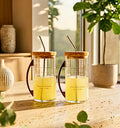 Set of two upcycled Ciroc glass sipper mugs with metal handles on a wooden table