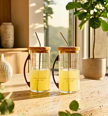Set of two upcycled Ciroc glass sipper mugs with metal handles on a wooden table"