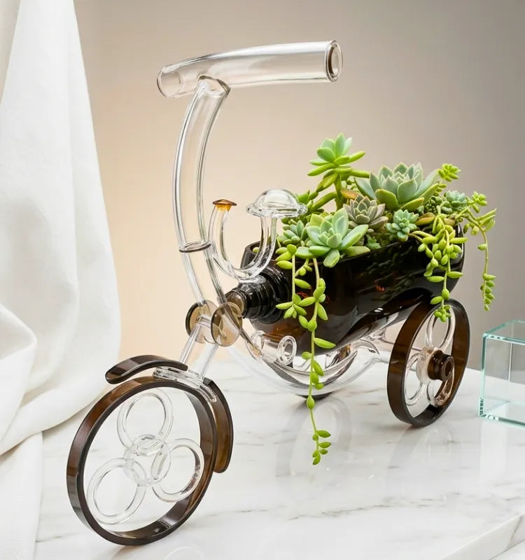 Brown upcycled glass bottle planter shaped like a tricycle on a plain background